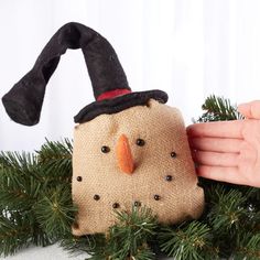 a hand is holding a small bag with a snowman on it and a black hat