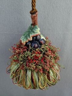 an ornament hanging from a rope with berries and leaves on it's side