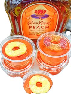 four orange jellos in plastic containers next to a bottle of booze punch