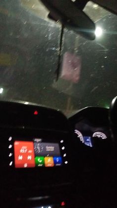 the interior of a car with snow on the windshield and dash lights in the background