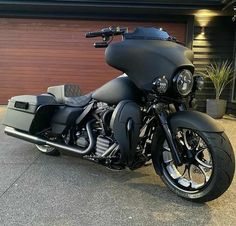 a black motorcycle parked in front of a garage