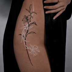 a woman's arm with a flower tattoo on her left side, which is drawn in white ink