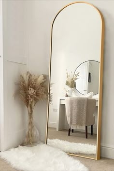 a large mirror sitting on top of a floor next to a white chair and table