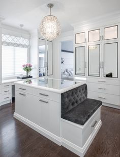 a white kitchen with an island bench and chandelier