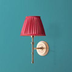 a red lamp on a blue wall next to a white light fixture with a pink shade