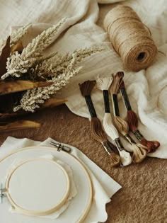 the table is covered with white linens and various crafting supplies such as yarn, scissors, thread, and spools