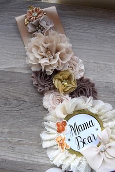 a close up of a flower decoration on a wooden surface with the name mama bear written on it