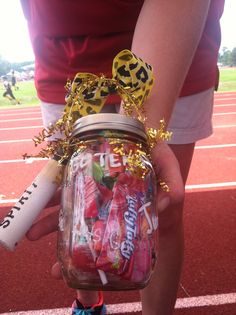 a person holding a jar full of candy and a baseball bat in their hand on a track