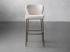 an upholstered bar stool in a room with concrete flooring and white walls