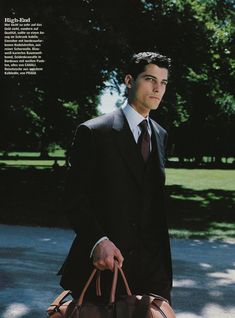 a man in a suit and tie holding a brown bag