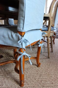 a dining room table and chairs covered in blue linens with ties on the back