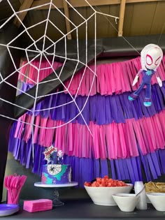 a table topped with plates and bowls filled with cake next to spider webs hanging from the ceiling