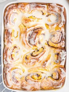 a pan filled with cinnamon rolls covered in icing