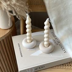 two white candles sitting on top of a book