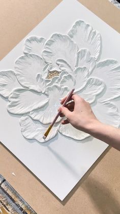 a person is painting a flower on a piece of white paper with a paintbrush