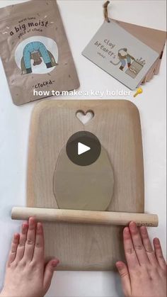 two hands are holding a wooden board with an animal on it and another hand is holding a stick