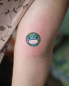 a person with a small tattoo on their arm that has a globe in the middle