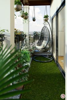 an outdoor area with grass, plants and hanging chairs on the side of a building