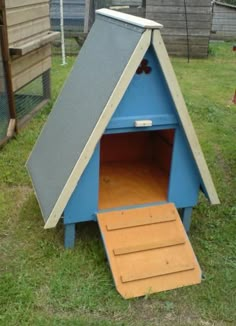 a blue dog house with steps leading up to it's door and the roof open