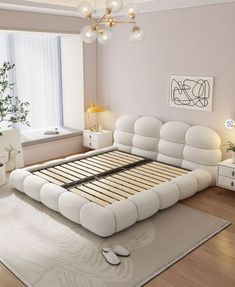 a white bed sitting on top of a hard wood floor next to a large window