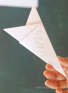 a hand holding an origami paper airplane