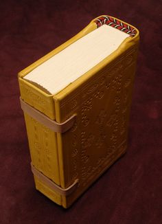 a small yellow box sitting on top of a brown table next to a red wall