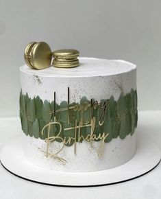 a white cake with green frosting and gold decorations on it's top that says happy birthday