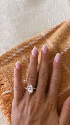 a woman's hand with a diamond ring on her finger, resting on a blanket