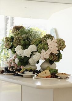 a table topped with plates and vases filled with different types of flowers on top of it