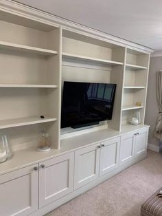 a living room with white bookcases and a flat screen tv on the wall