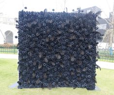 a large black sculpture sitting on top of a lush green field