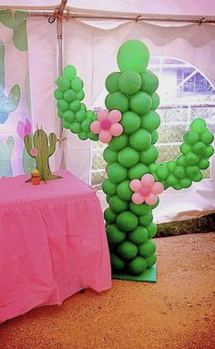 there is a large balloon cactus next to a table with a pink cloth on it