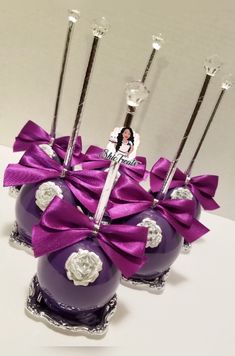 two purple vases with silver handles and bows on them, one is filled with candles