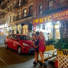 two women are standing in front of a store at night with their hands on each other's hips