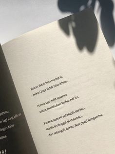 the shadow of a person's hand on top of an open book with text