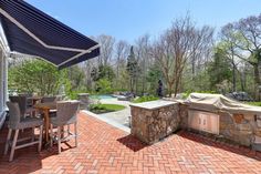 an outdoor kitchen and dining area with brick flooring