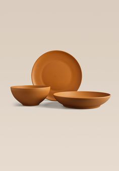 three orange bowls and one plate on a white background