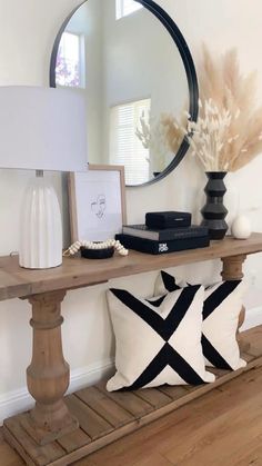 a wooden table topped with a mirror and vase filled with flowers