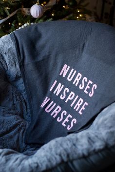 a blanket that says nurses inspire nurses sits on a chair in front of a christmas tree