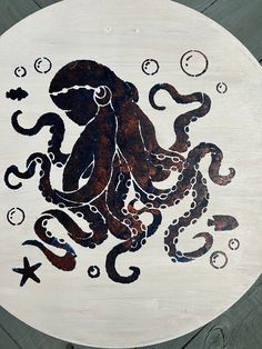 an octopus is painted on the side of a white plate with black and brown designs