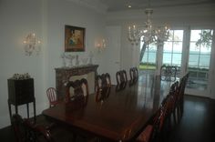 a dining room table with chairs and chandelier in front of an open window