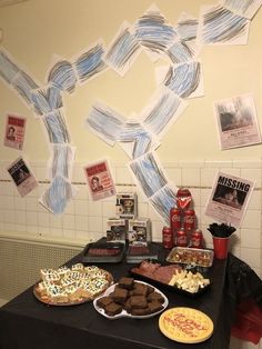 a table topped with lots of food next to a wall covered in pictures and papers