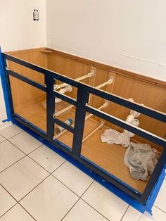 an unfinished kitchen cabinet with blue trim and glass doors on the bottom, in front of a tiled floor