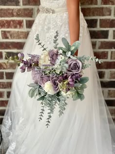 a bridal holding a bouquet of flowers in front of a brick wall