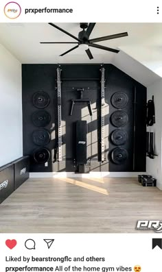 an empty room with black walls, ceiling fan and speakers on the wall in front of it