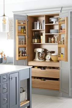 an open cabinet in the middle of a kitchen with lots of cupboards and drawers