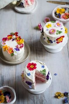 a cake with white frosting and colorful flowers on the top is cut in half