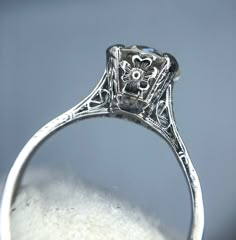 an antique style diamond ring with filigrees on the sides and flowers in the center