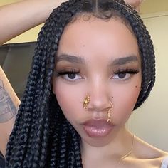 a woman with braids and piercing on her nose