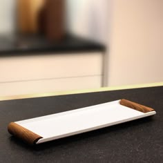 an empty white plate sitting on top of a counter next to a brown and black object